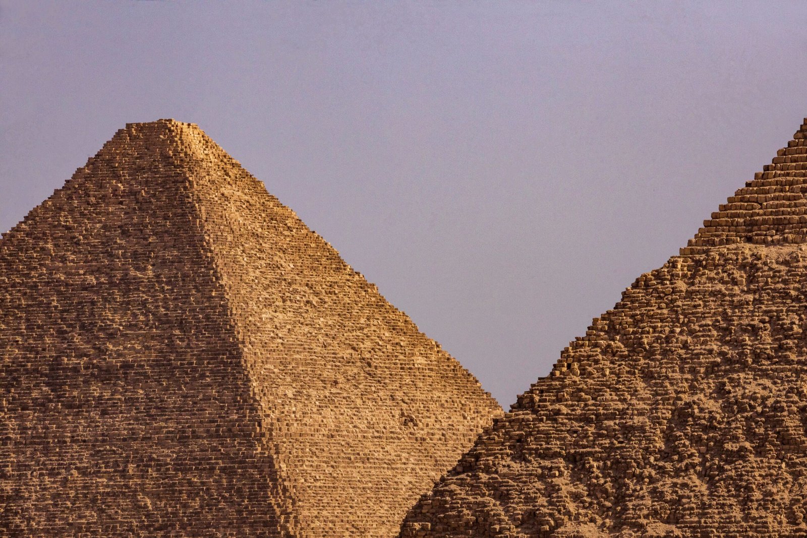 A close-up view of two iconic Egyptian pyramids under a clear blue sky.