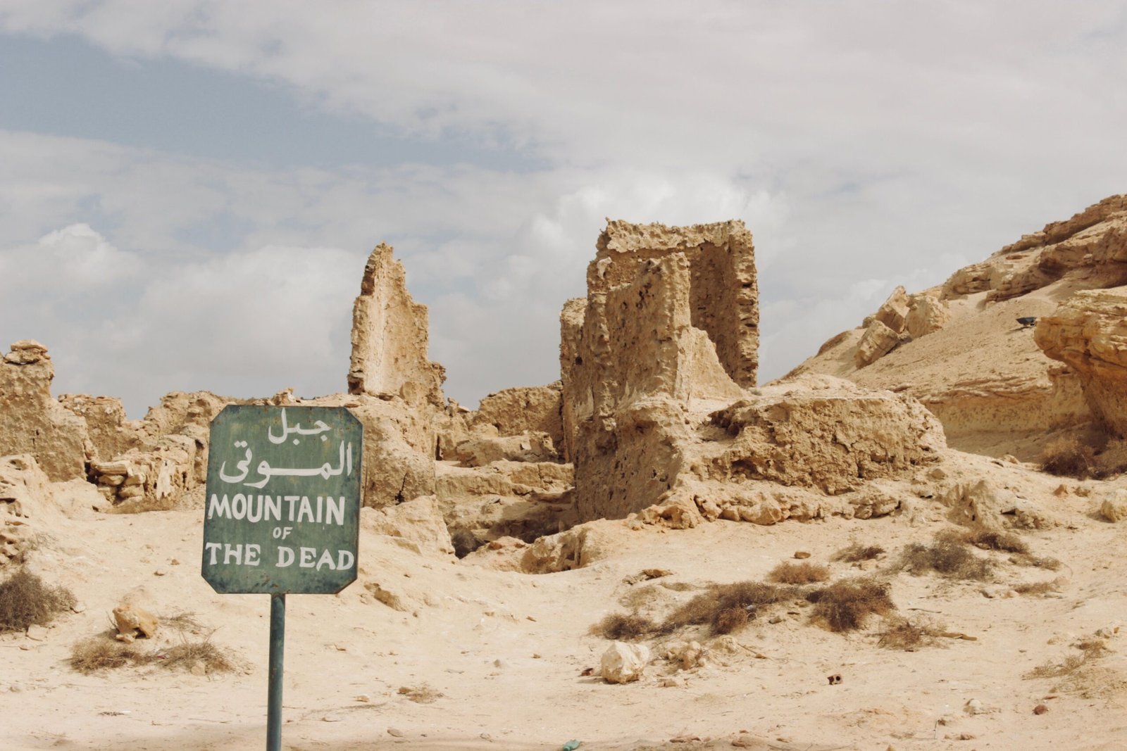 Ancient ruins of Mountain of the Dead with cloudy sky in Egypt's desert landscape.