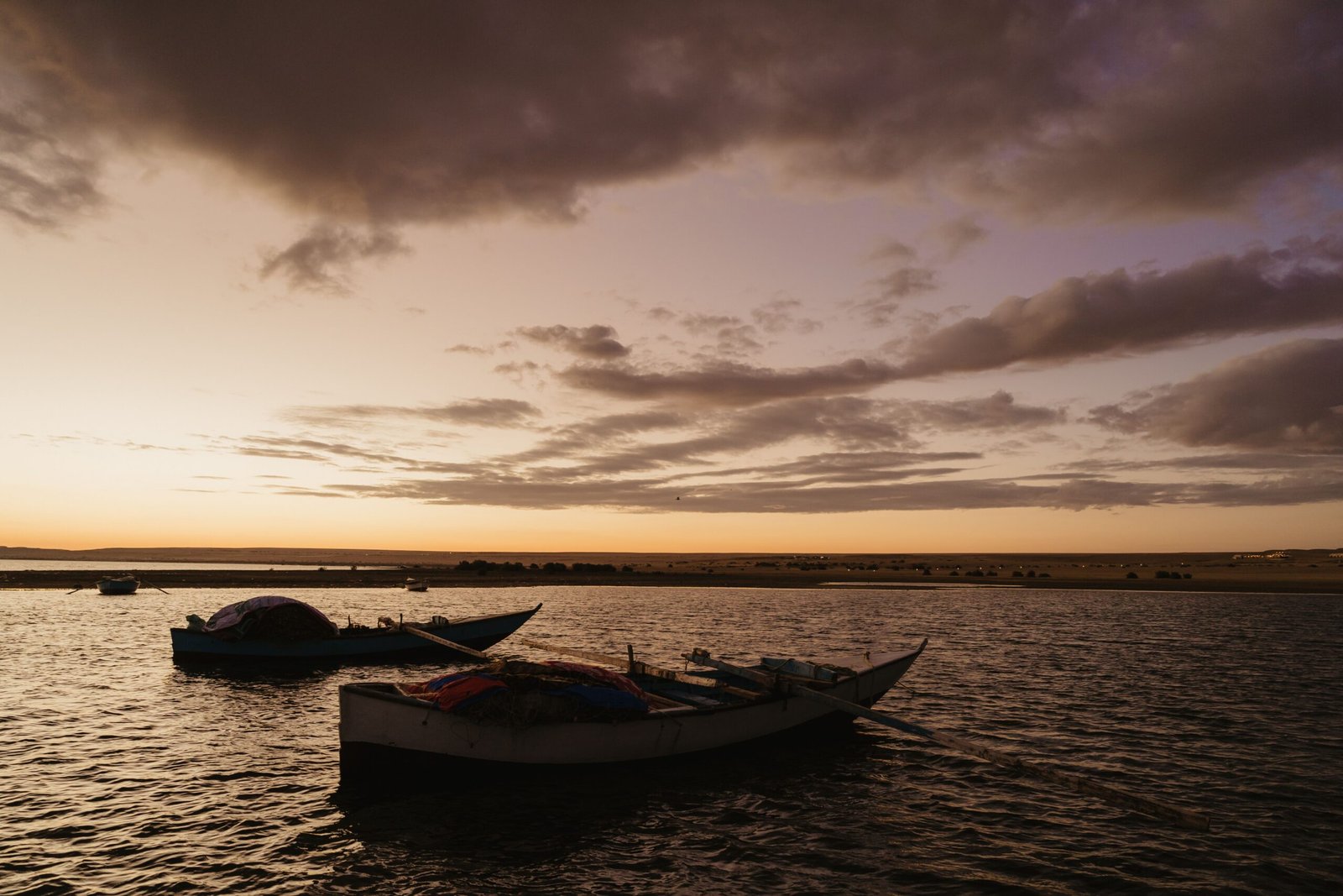 Tranquil boats silhouetted at sunset over Lake Qarun, Faiyum, Egypt.
