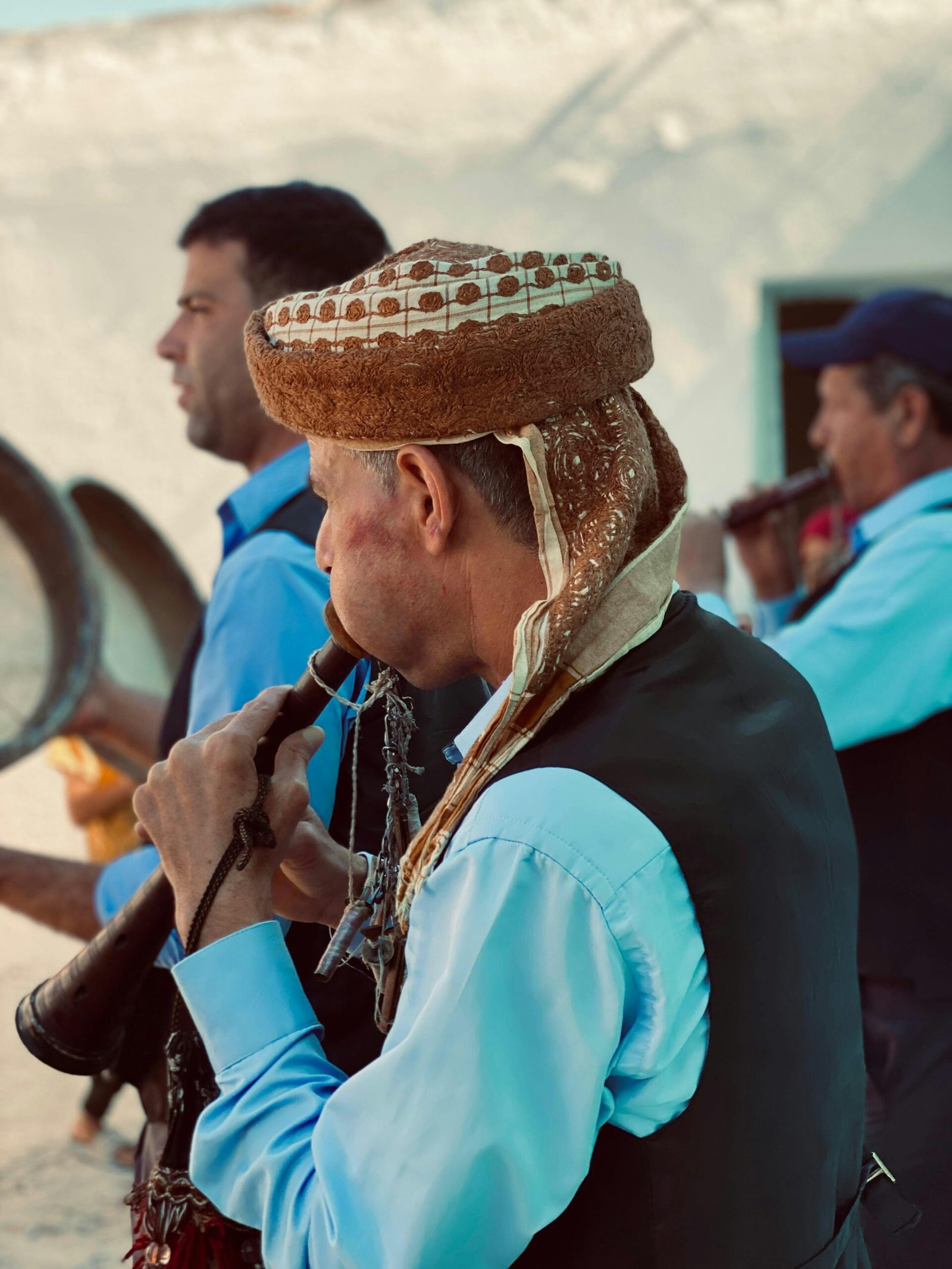 Musicians in traditional attire playing wind instruments outdoors at a cultural festival.