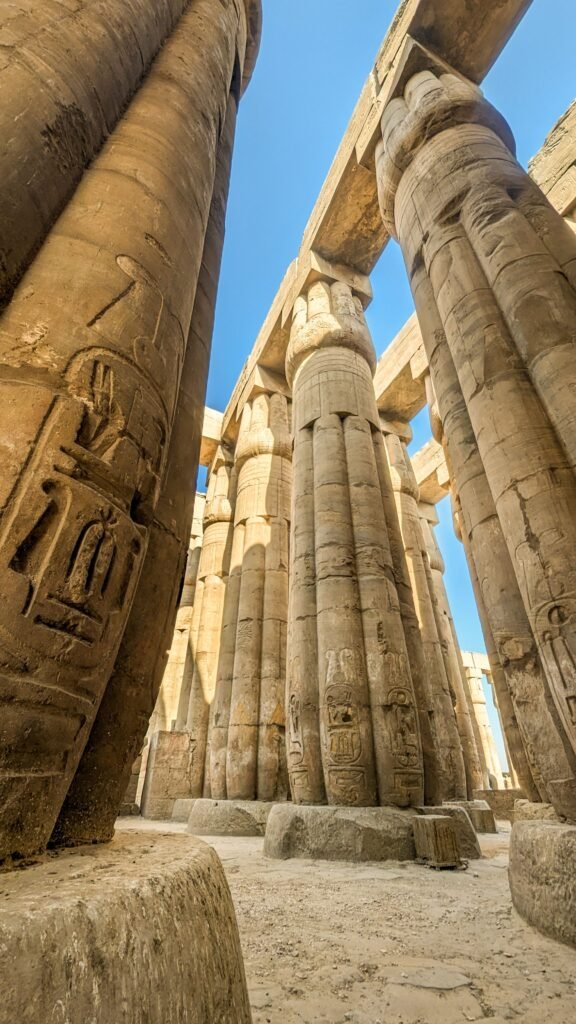 Explore the impressive stone columns of an ancient Egyptian temple under a clear blue sky.