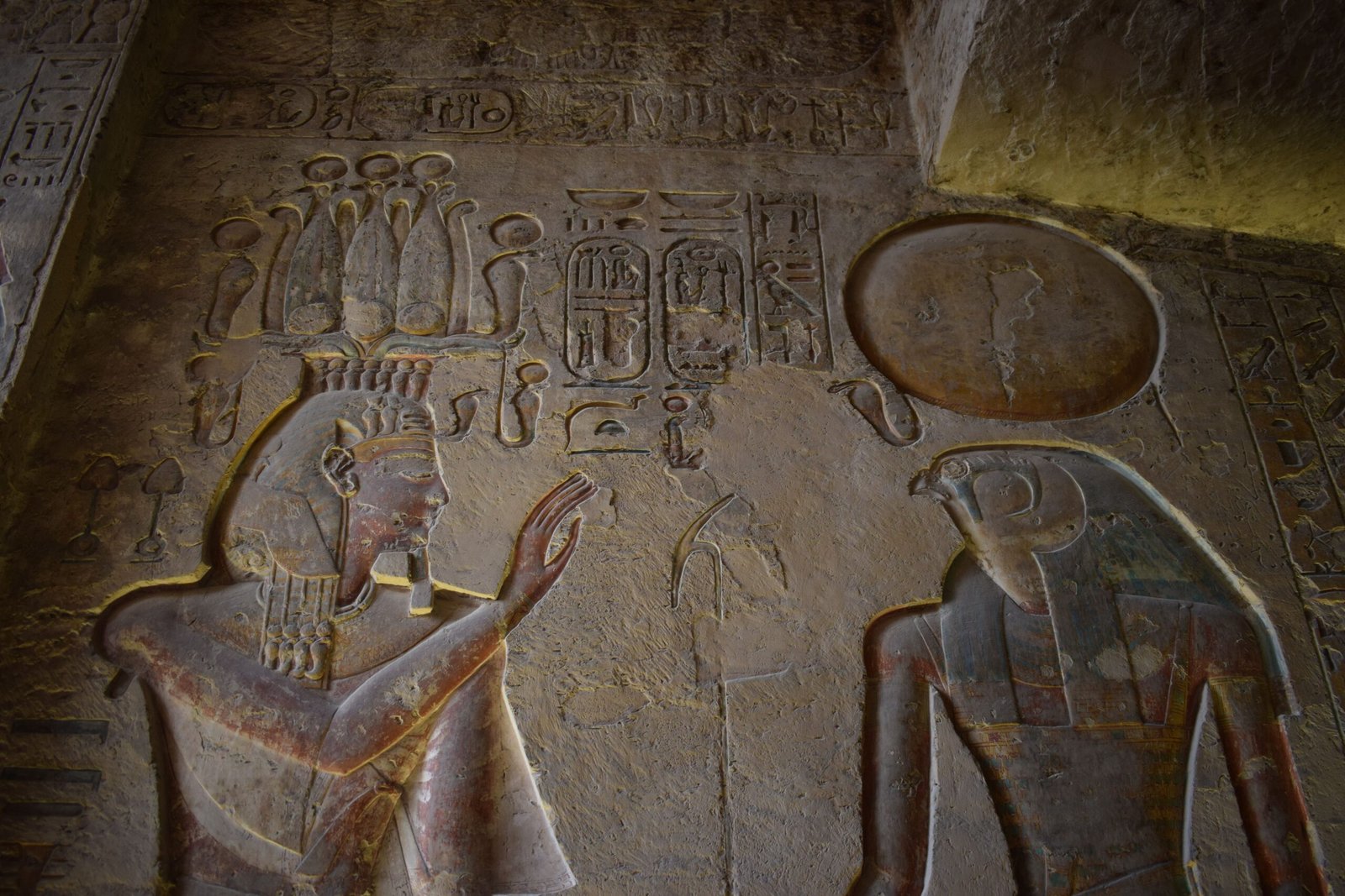 Detailed ancient Egyptian relief carvings of gods in a historic temple setting.