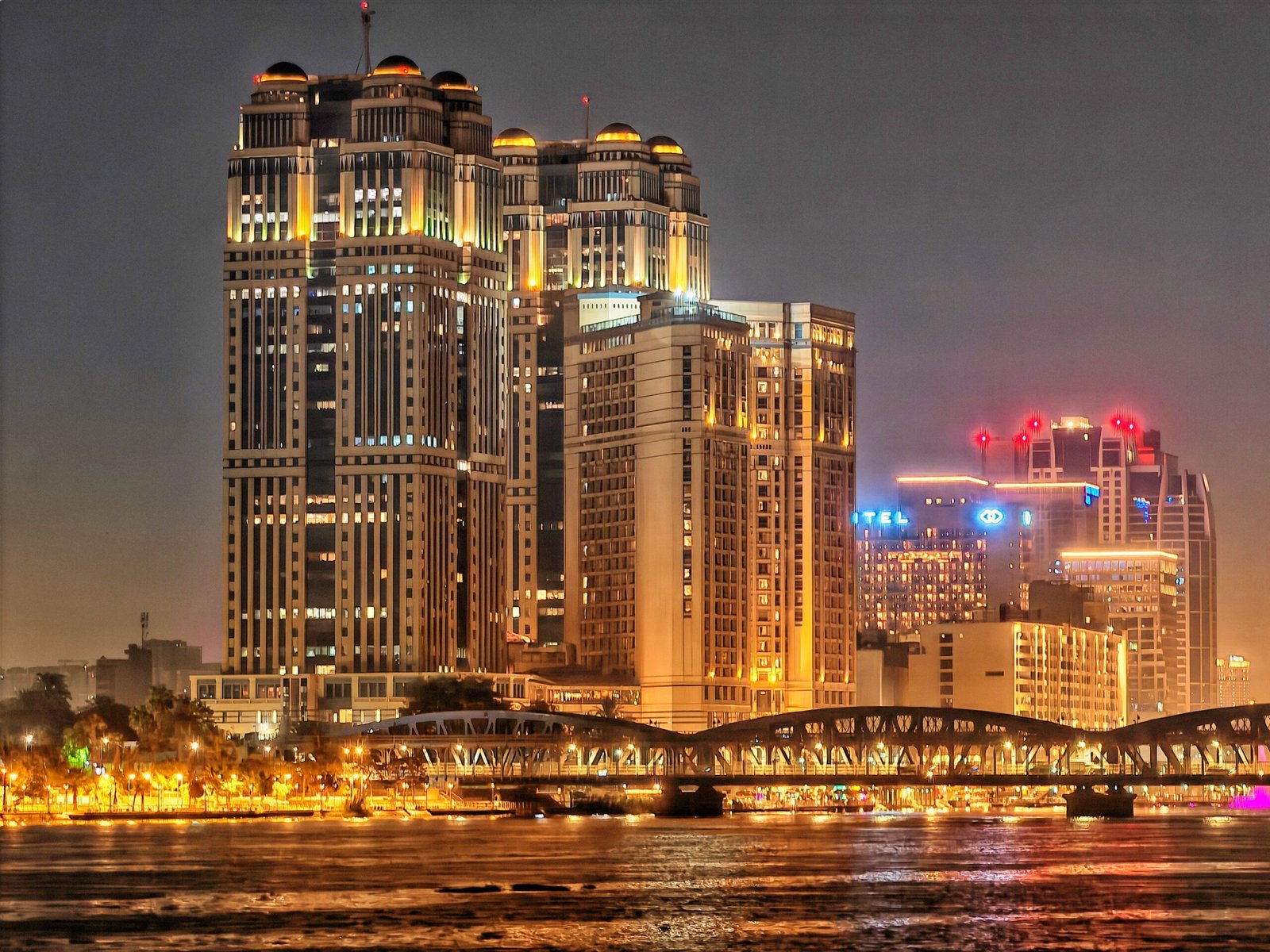 Stunning night view of illuminated skyscrapers and a bridge reflecting on the river.