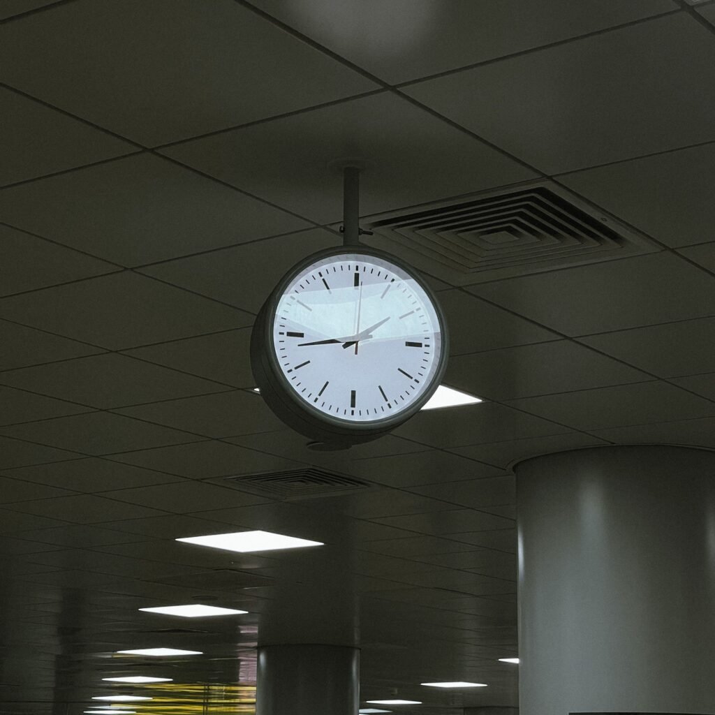 A ceiling-mounted clock in a modern indoor environment with fluorescent lighting.
