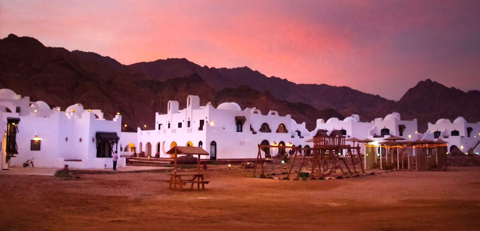 Stunning sunset over a traditional resort set against desert mountains.