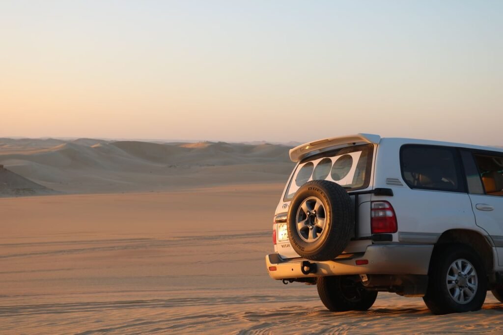 An SUV parked on a serene desert landscape at sunset, capturing adventure and tranquility.